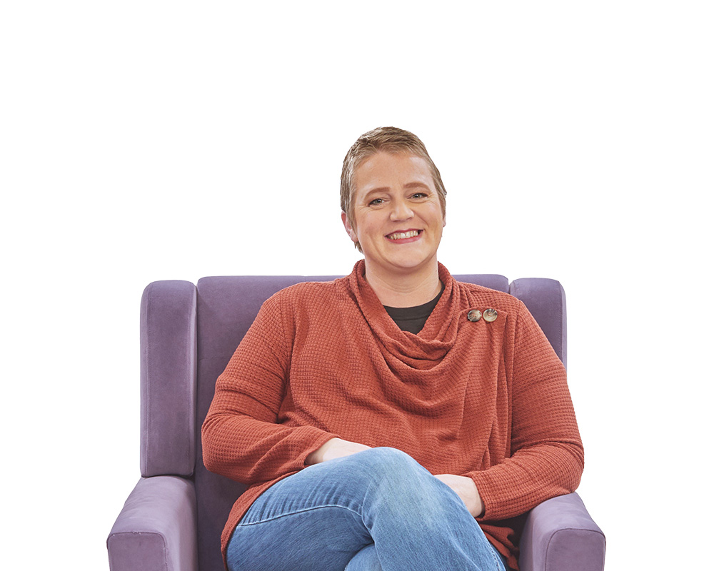 Young woman sitting in chair smiling.