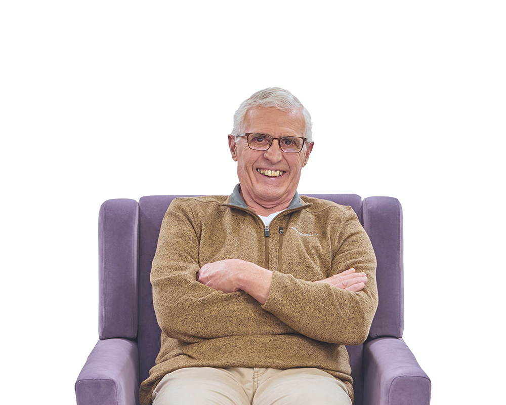 Senior man sitting in chair smiling.