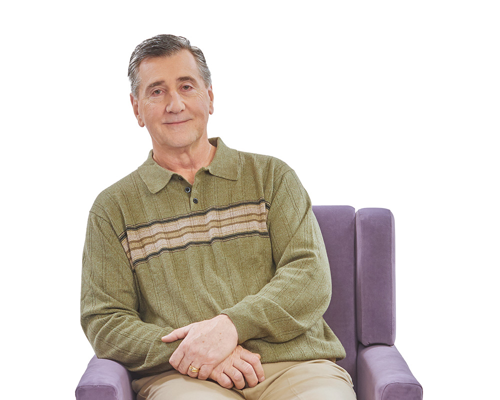 Middle-aged man sitting in chair smiling.