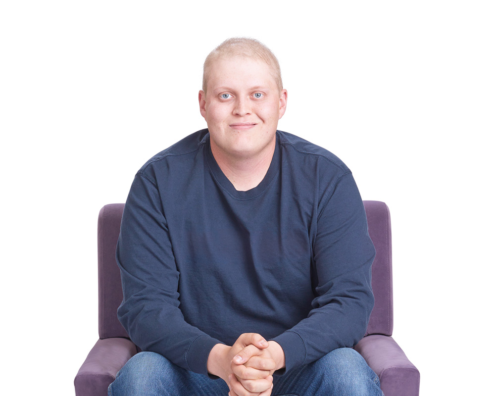 Young man sitting in chair smiling.